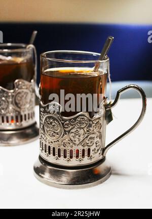 Glasses in metal holders with brewed tea bags on a table in a train compartment Stock Photo