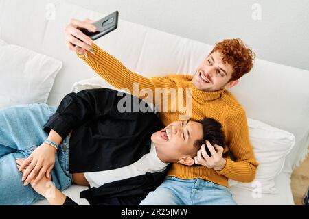 Gay couple taking a selfie lying on the sofa Stock Photo