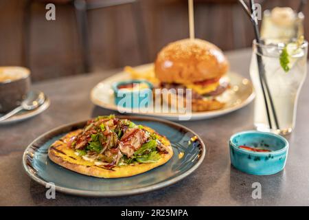 burger and kebab on bread with sauces served on the table in the restaurant. Stock Photo
