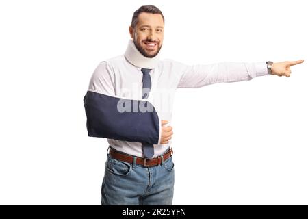 Injured man with an arm sling and cervical collar smiling and pointing to the side isolated on white background Stock Photo