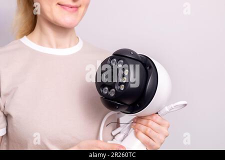 Smiling Caucasian Woman Holds IP Alarm Security System, Intruder Video Monitoring, Surveillance Camera For Smart Secure Home, House. Safety From Stock Photo