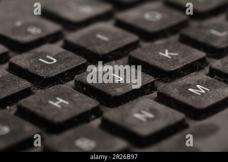 front view closeup of old black keyboard with keys covered in dust and dirt isolated on white background Stock Photo