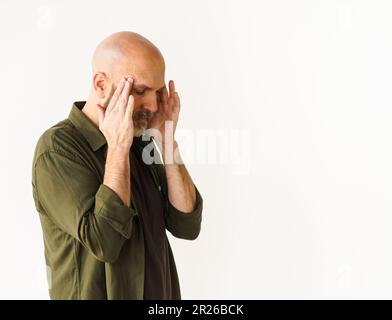 Mature man experiencing headache holds head with both hands. Concept of headache, conveying pain and discomfort that can accompany such experience. . High quality photo Stock Photo