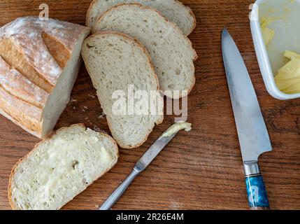 Sliced bread on a wooden chopping board, battered sandwich, morning domestic breakfast routine. Stock Photo