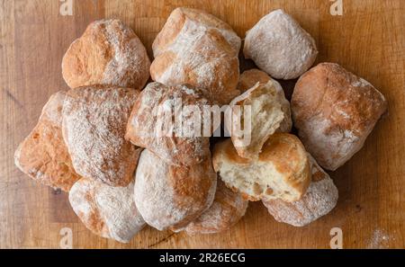 A pile of freshly baked ciabatta white crusty home-made rolls on a rustic wooden table, Top view, Side view. Stock Photo