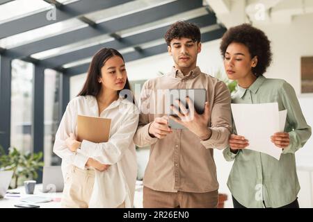 Three Business Coworkers Using Digital Tablet Standing In Modern Office Stock Photo