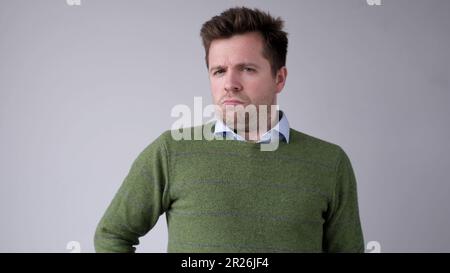 European, young man, shakes his head in disbelief and looks skeptically into the camera Stock Photo