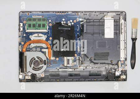 Disassembled laptop on a white background. Isolated. Broken dusty computer in a service workshop for cleaning and repair. Computer motherboard, chips Stock Photo