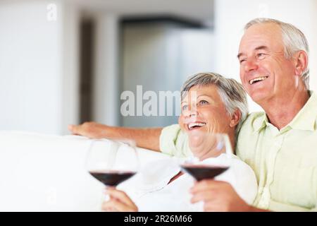 Relaxed mature couple drinking wine. Relaxed mature couple drinking wine while resting on couch. Stock Photo