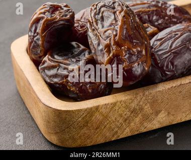 Ripe large dates in a wooden plate Stock Photo