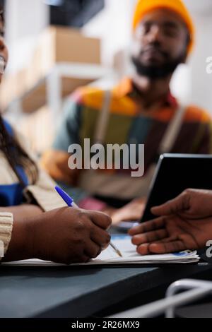 Warehouse worker hand writing in clipboard at reception desk Stock Photo