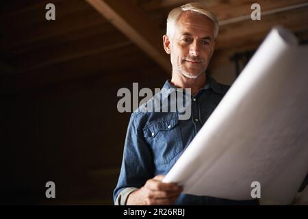 He couldnt wait to say I made this. a senior man holding a blueprint. Stock Photo