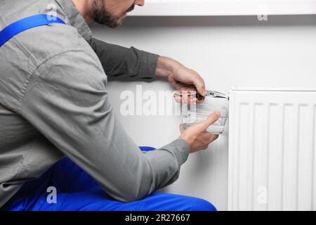 Professional plumber using pliers while preparing heating radiator for winter season, closeup Stock Photo