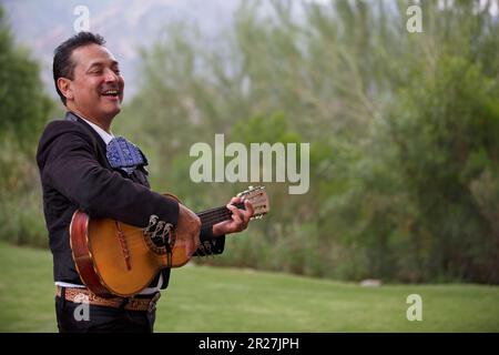 Mariachi musician singing and playing a vihuela outdoors in Tucson, Arizona Stock Photo