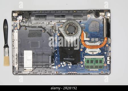 Disassembled laptop on a white background. Isolated. Broken dusty computer in a service workshop for cleaning and repair. Computer motherboard, chips Stock Photo