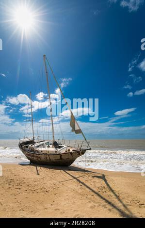 Having broken its mooring during stormy weather an old abandoned sailing Yacht lays stranded at Yorkeys Knob Beach in Cairns, Queensland in Australia. Stock Photo