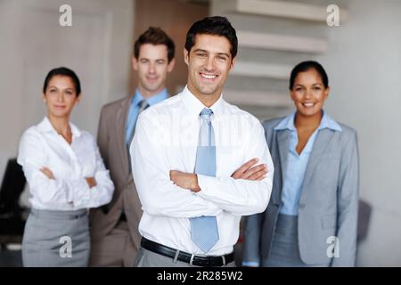 Young business leader with his team. A young business leader standing in front of his team smiling confidently. Stock Photo