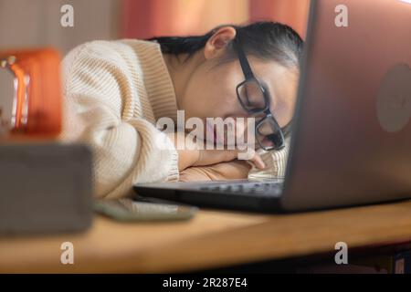 Woman sleeping with laptop in home office after long hours of work. Stock Photo