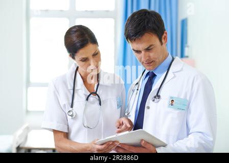 Making sure theyre on the right track. a serious medical team going through a patients chart. Stock Photo