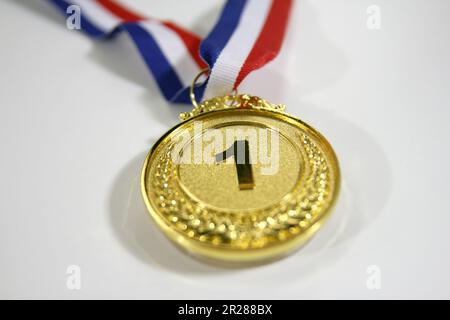Gold medal 1 place with a ribbon on a light gray background, the concept of victory or success Stock Photo