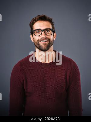 Making a face. Studio shot of a handsome young man pulling funny faces against a gray background. Stock Photo