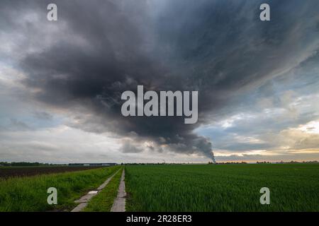 Dark smoke and clouds emanating from a distant fire cover the sky Stock Photo