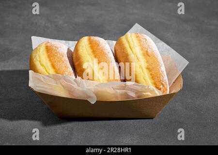 freshly baked jelly donuts in take away tray on dark grey background Stock Photo