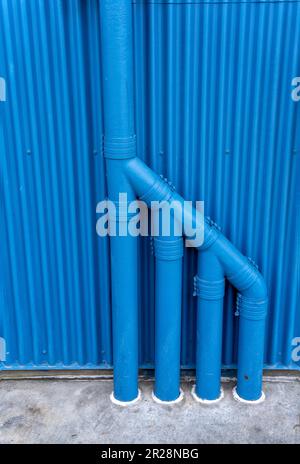 Blue pipes against metal siding wall Stock Photo