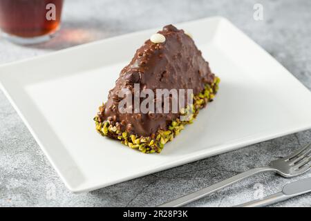 Dessert Cake from Malaga on stone table. Cake with banana inside, covered with chocolate sauce and hazelnuts Stock Photo