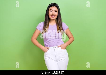 Photo portrait of pretty vietnamese chinese young girl hand pockets posing dressed stylish violet outfit isolated on green color background Stock Photo
