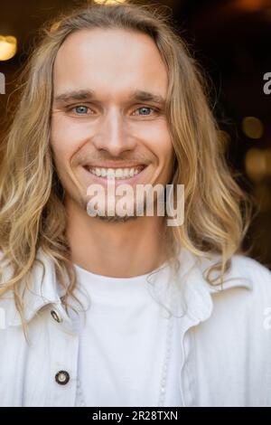 portrait of young and carefree yoga man with long fair hair looking at camera outdoors Stock Photo