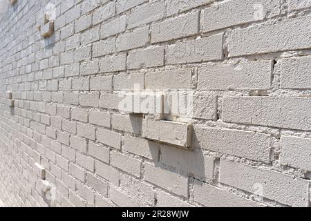 Beige brick wall with embossed bricks on sunny day. Stock Photo
