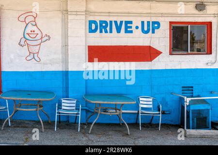 A painted sign on the wall that points the way to the drive through Stock Photo