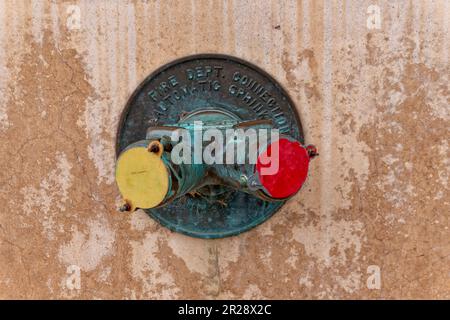 Old standpipe fire department connection on the weathered cracked wall Stock Photo