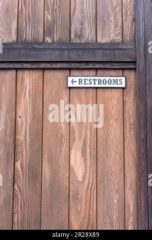 Restrooms sign with arrow on the wooden fence Stock Photo