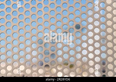 Close up of a perforated metal sheet with scratches on a fence Stock Photo