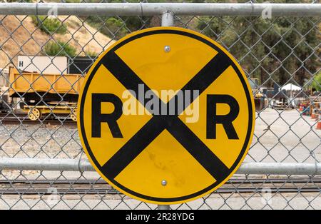 Rail road crossing sign on metal fence Stock Photo