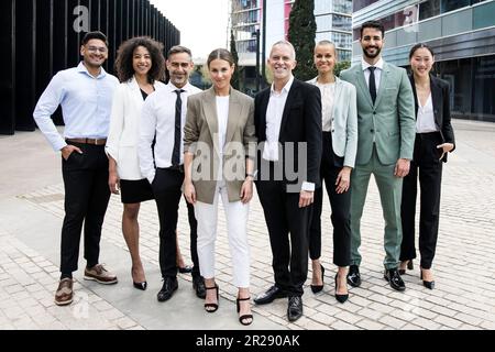 Group of smiling multiethnic businessman and businesswoman staring at camera outside. Multiracial cheerful confident executive team standing in the Stock Photo