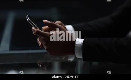 Close up cropped view of African male hands holding smartphone while sitting at table Stock Photo
