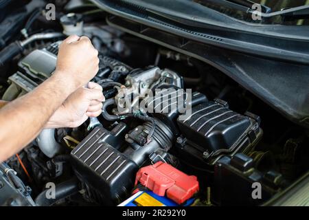 Concept of engine maintenance. Mechanics hold wrench to tighten bolts in engine repairs. Car engine turned off. Engineers are checking combustion syst Stock Photo