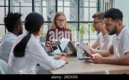 Team Working At Desks In Busy Office Stock Photo