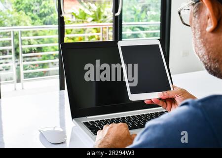 Closeup, People using the device home. A man holds a tablet to use the internet in the living room at home during the day Color tablet for sale, blank Stock Photo