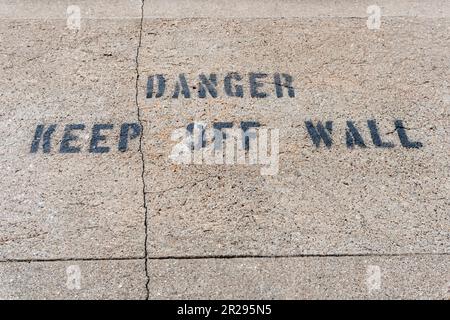 Danger keep off wall text on cracked concrete wall Stock Photo