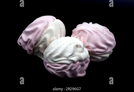 White and pink fluted marshmallows on a black background. Whole and broken off piece. Subject photo. Photo in high quality. Horizontal Stock Photo