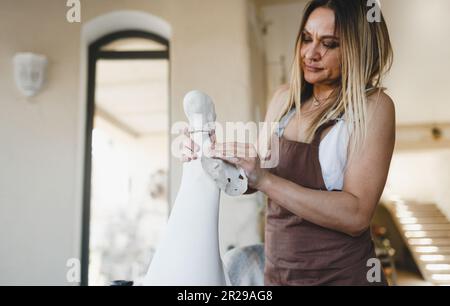 a woman is working on a statue in her pottery workshop. Pottery work. Creation of clay products. Stock Photo