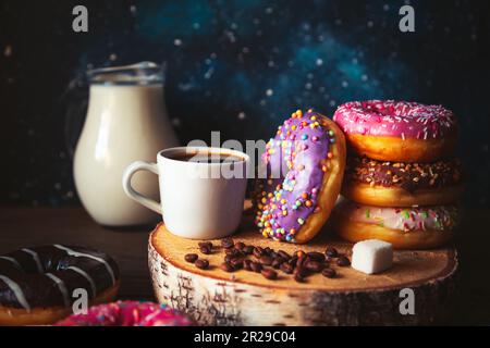 Stack of assorted donuts and a cup of coffee on a space background. Stock Photo