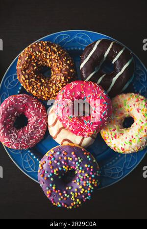 Plate with assorted donuts on the wooden table. Food background. Stock Photo