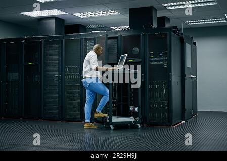 Server room, database and information technology with an engineer man at work on a network mainframe. Computer, programming and cybersecurity with a Stock Photo