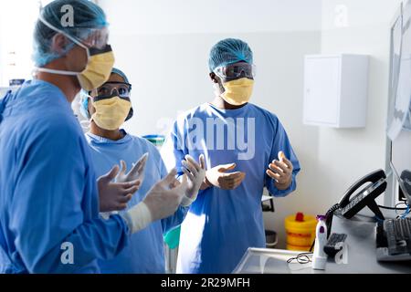 Diverse group of surgeons discussing x rays on screen in operating theatre Stock Photo