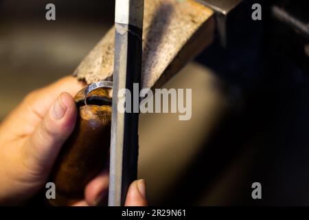 Close up of hands of caucasian female worker making jewellery using tools at jewellery workshop Stock Photo
